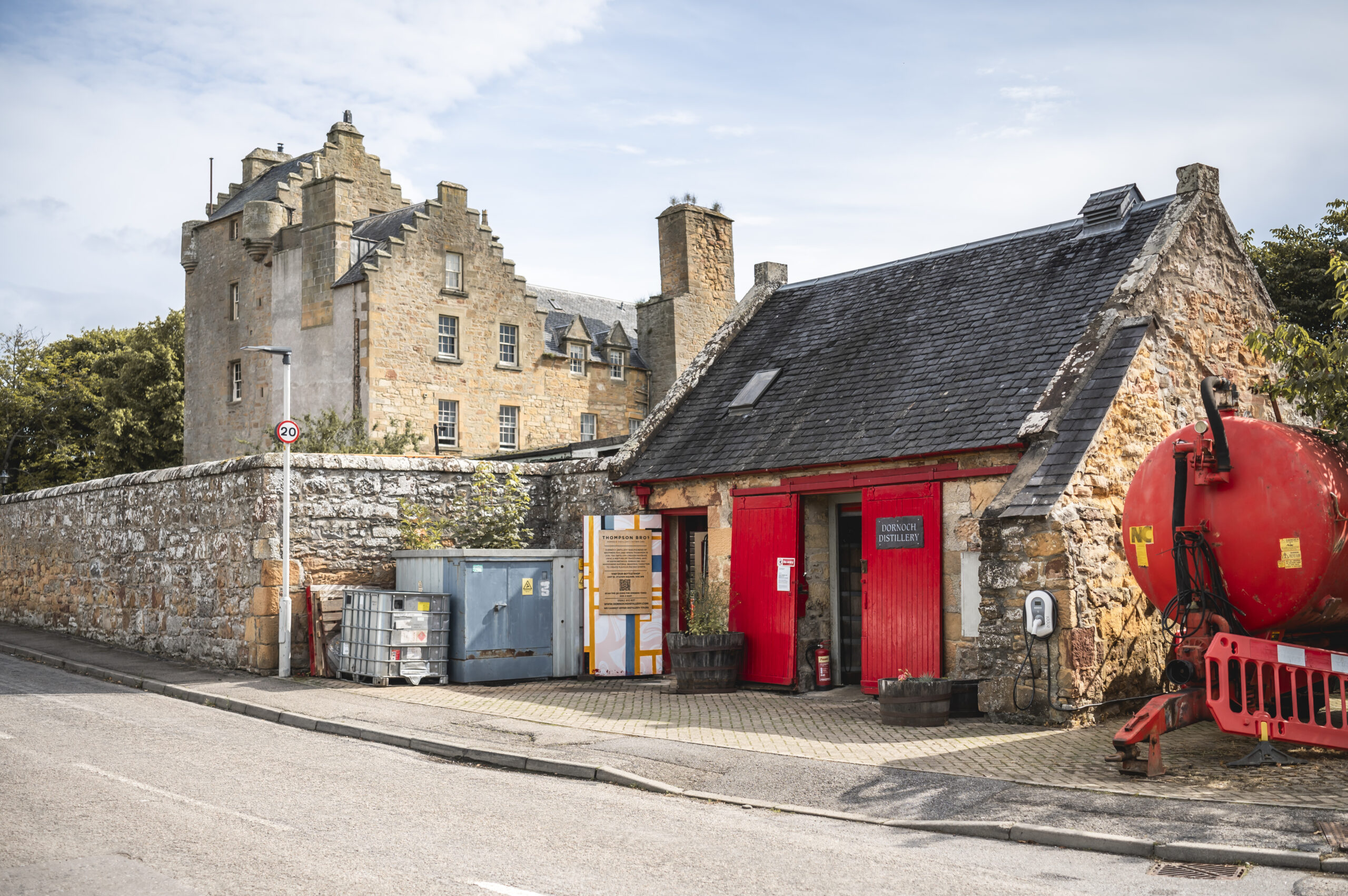 Exterior of Dornoch Distillery, the small red-door stone distillery beside Dornoch Castle Hotel.